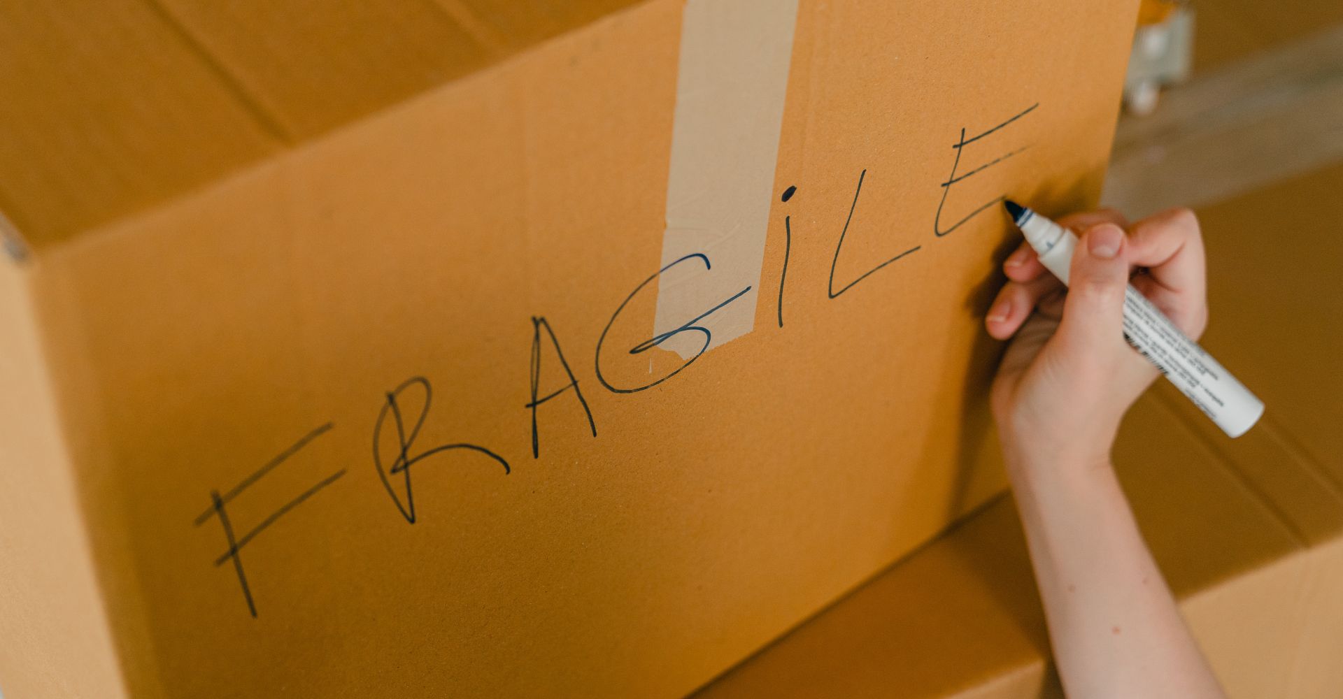 person writing fragile on a box